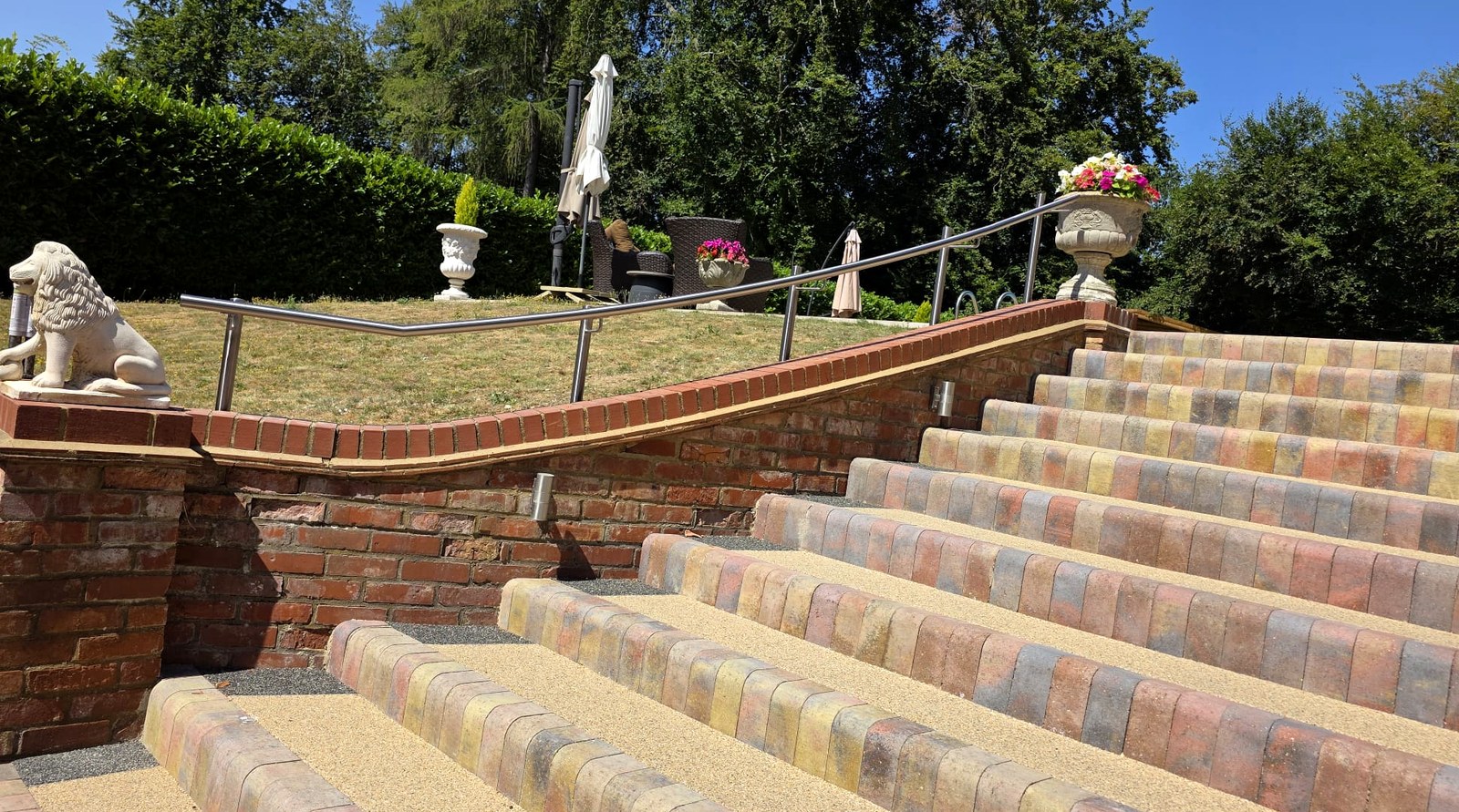 Curved brushed stainless steel handrail on posts following a semi-helical brick wall and steps, Beaconsfield